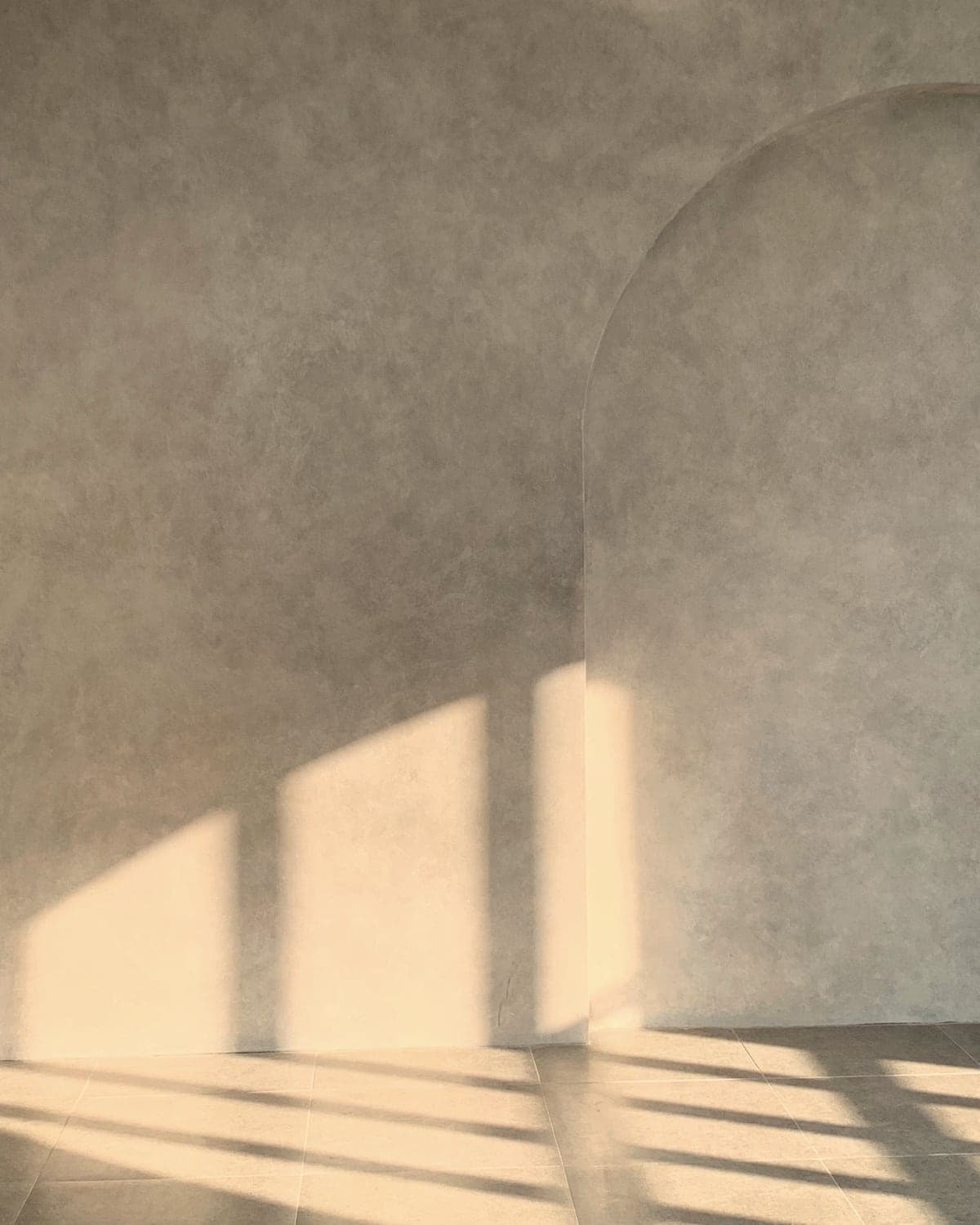Soft afternoon light falling across a plaster wall with an arched alcove.