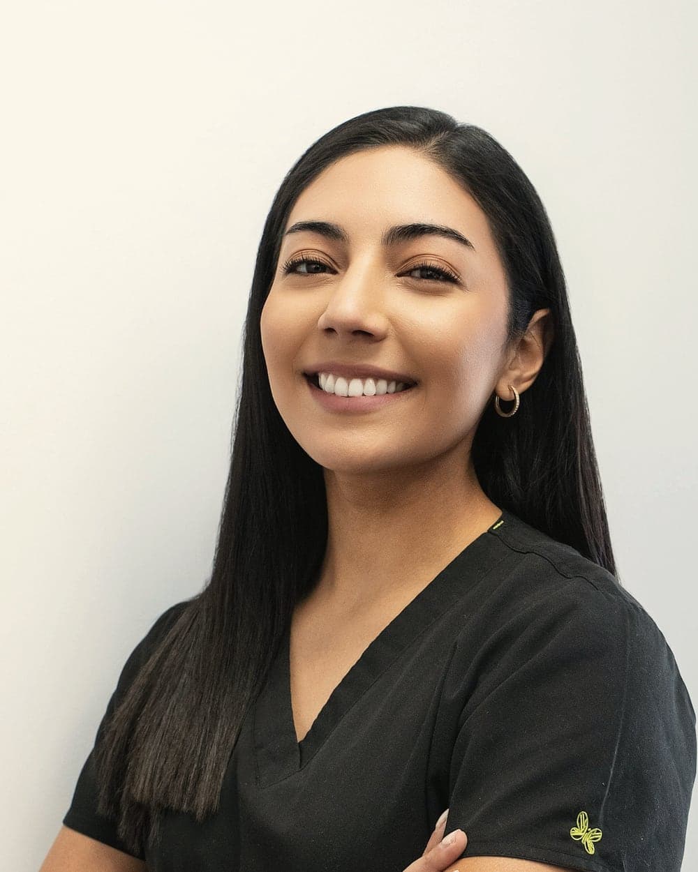Portrait of Dr. Ananya Rao, smiling, in dark scrubs.