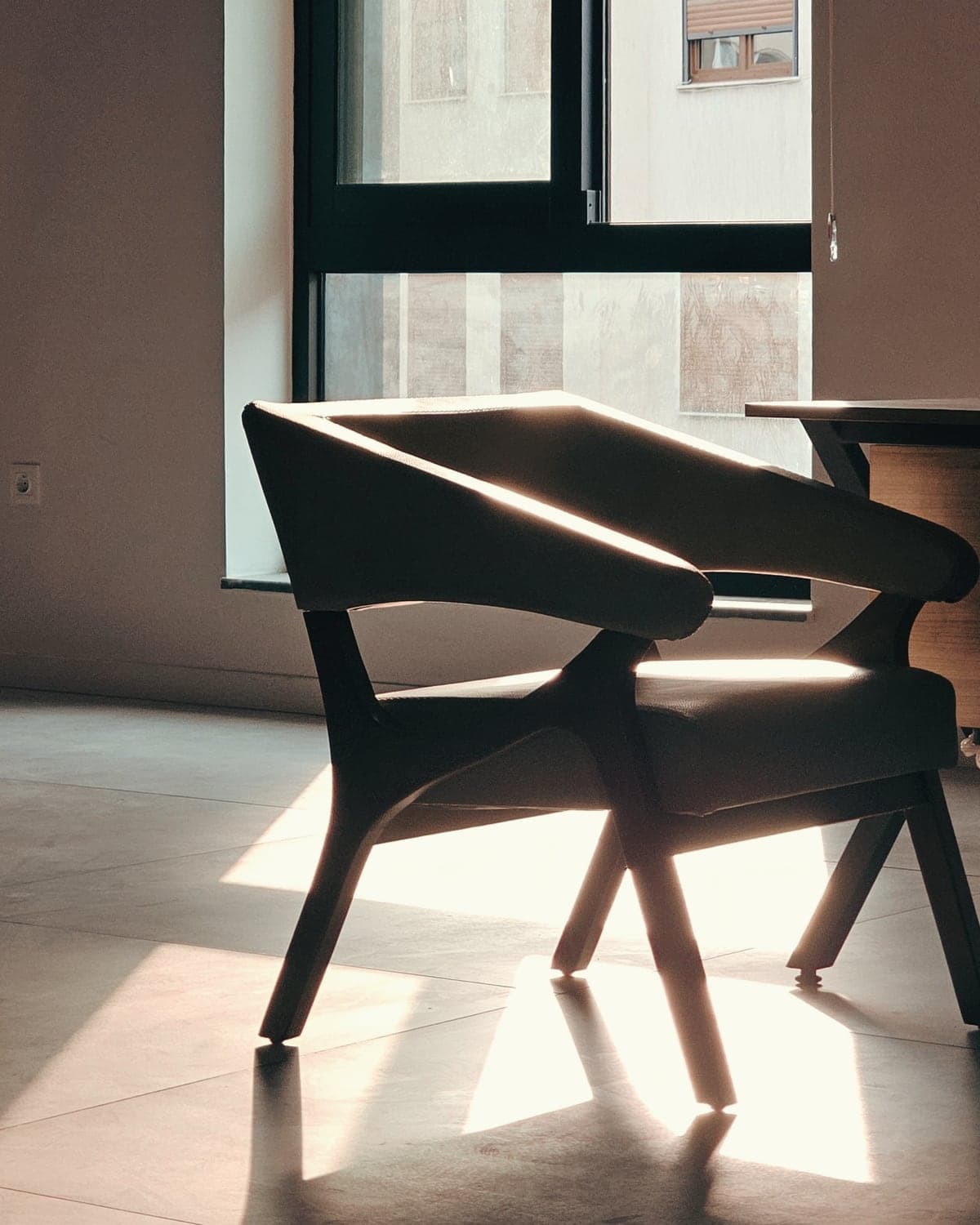An armchair in afternoon light beside a tall window.