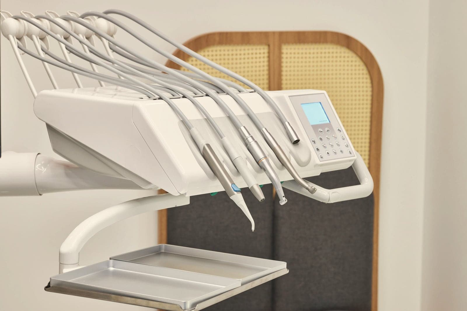 A dental instrument unit in front of an arched cane and oak panel in a bright treatment room.